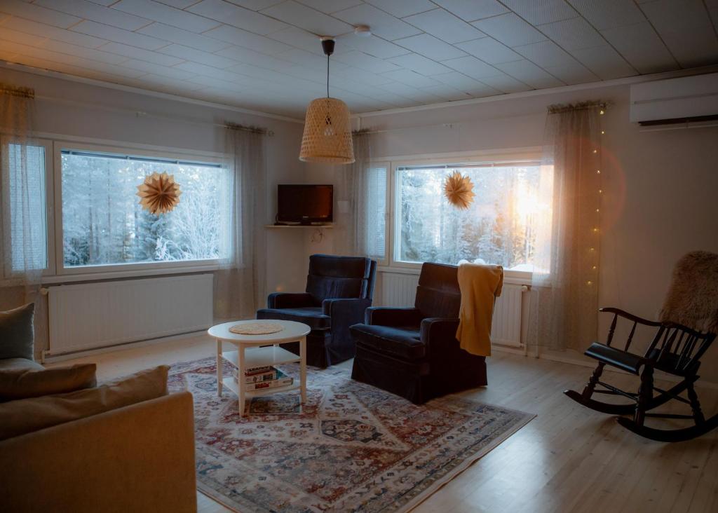 ein Wohnzimmer mit Sofa, Stühlen und Fenstern in der Unterkunft Talo Mustikankukka Tervola, Finland in Tervola