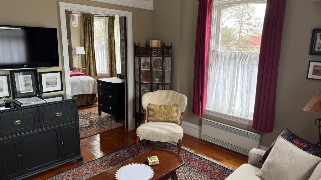 a living room with a bed and a tv and a chair at The 1885 Suites in Picton