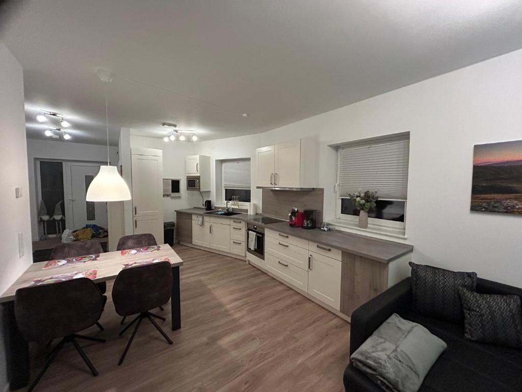 a kitchen and living room with a table and a couch at Moderne Ferienwohnung Green Garden mit Garten und Stellplatz in Bremerhaven