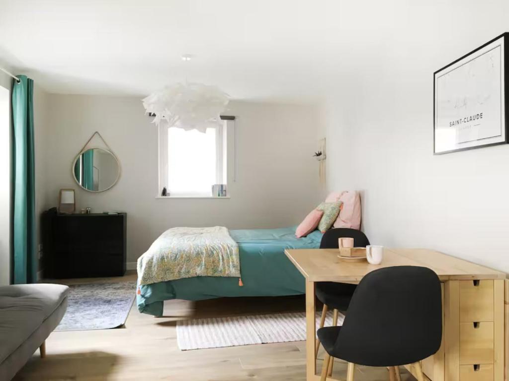 una camera da letto con un letto, un tavolo e delle sedie di Joli studio zen et cozy au coeur de Saint Claude a Saint-Claude