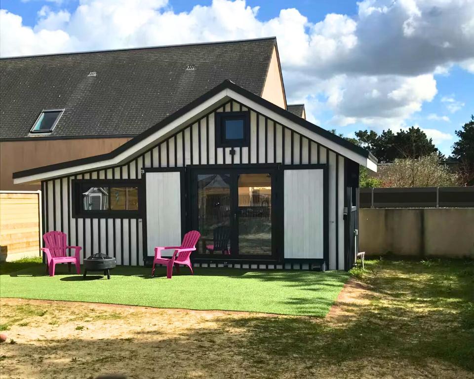 a black and white house with pink chairs in the yard at Le Cabanon - Tiny House 150m de la Plage in Portbail