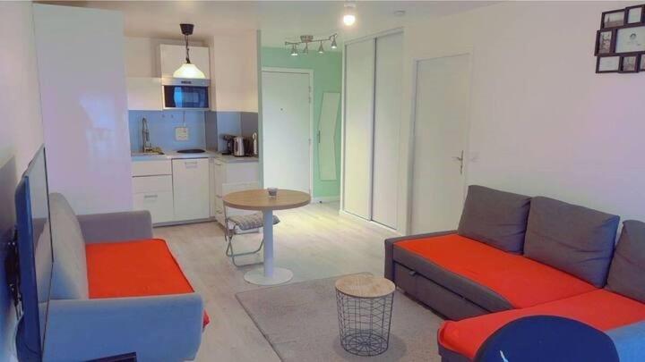 a living room with a couch and a table and a kitchen at Ducastel F2 Appartment in Juvisy-sur-Orge