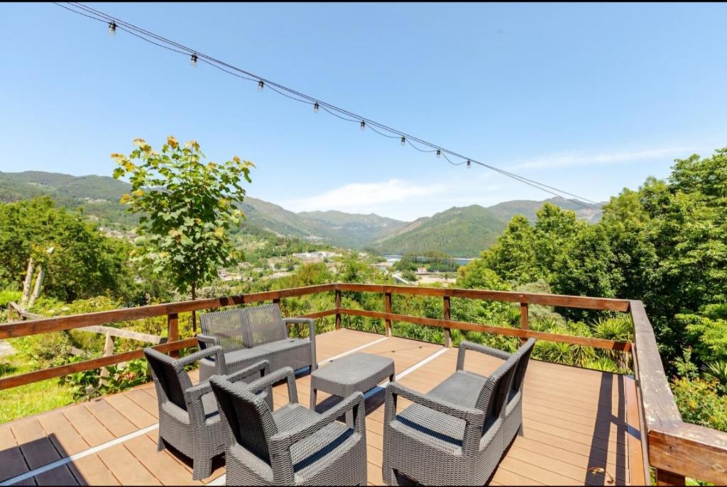 a deck with chairs and a table with mountains in the background at Casa Soutinho - Gerês in Ventosa