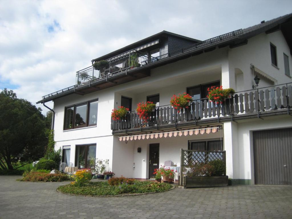 ein weißes Haus mit Blumenkästen auf den Balkonen in der Unterkunft Ferienwohnung Anita Müller in Schmallenberg