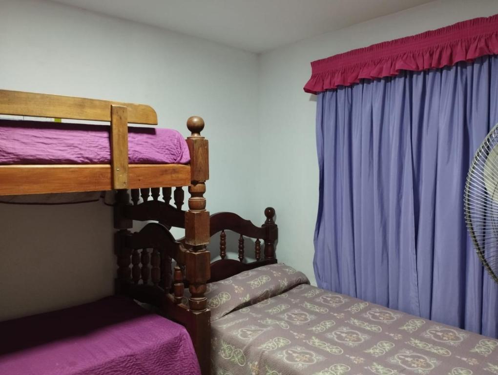 a bedroom with two bunk beds with purple curtains at Casa en San Pedro de Colalao in San Pedro de Colalao