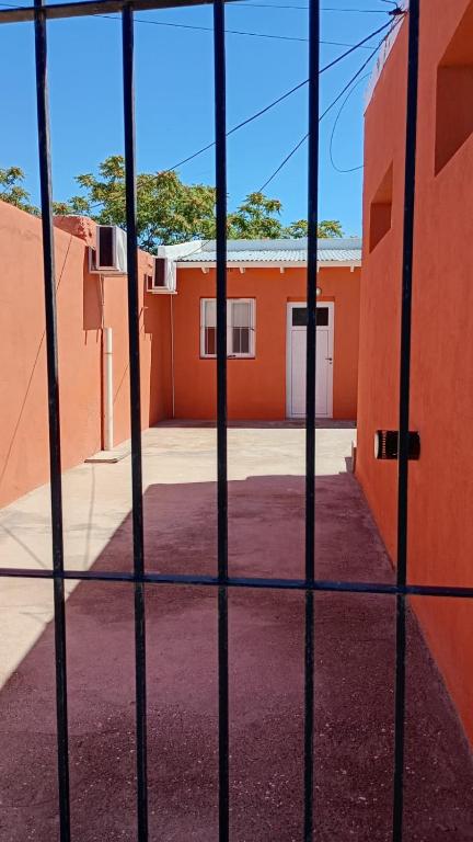 a view through a fence of an orange building at Dpto en San Antonio Oeste 2 pax in San Antonio Oeste