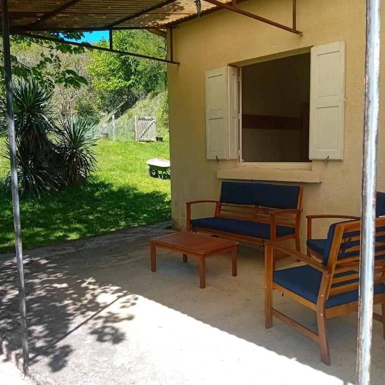 - une terrasse couverte avec 2 chaises, une table et une fenêtre dans l'établissement Maison dans écrin de verdure en Périgord noir, à Saint-Cyprien