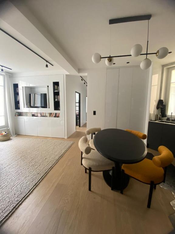 un salon avec une table et des chaises noires dans l'établissement 3 bedrooms luxury design by architect quiet good location 5 min walk from Paris 2 min from metro central line 1 and 7 min from wood and lake, à Saint-Mandé