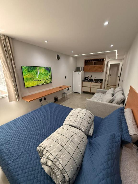 Hotel Juca Studio Botafogo, a bedroom with a blue bed and a living room at Juca Studio Botafogo in Rio de Janeiro