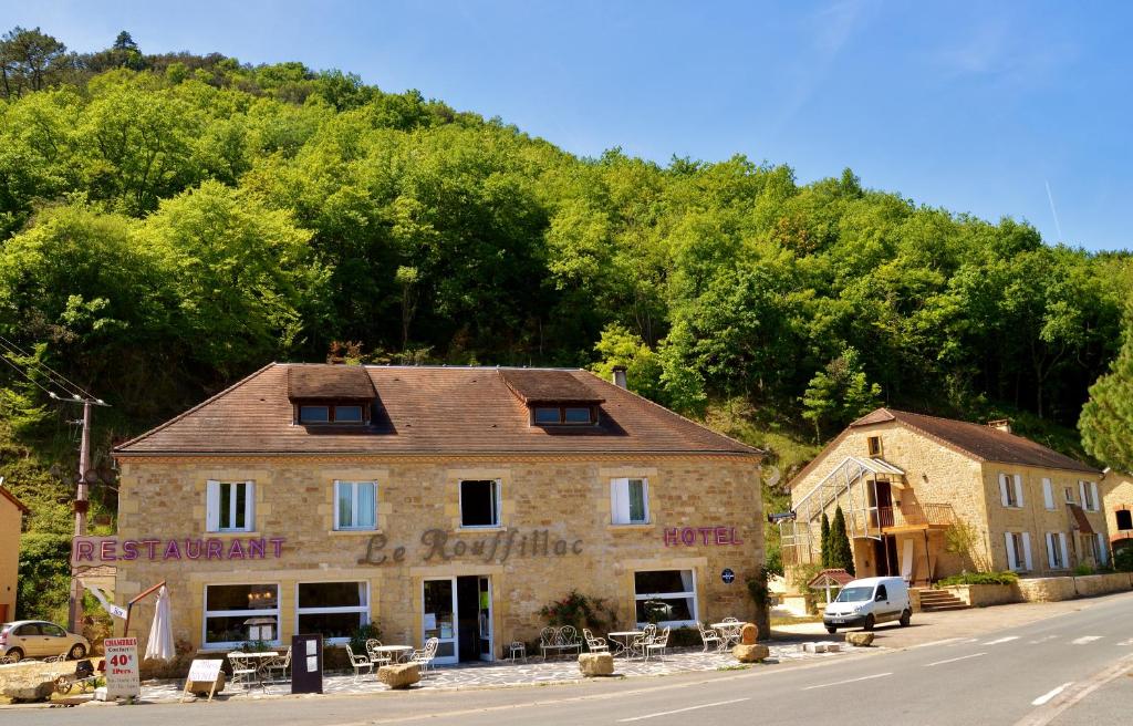 a building on the side of a road with trees at Hôtel-Restaurant Le Rouffillac in Carlux