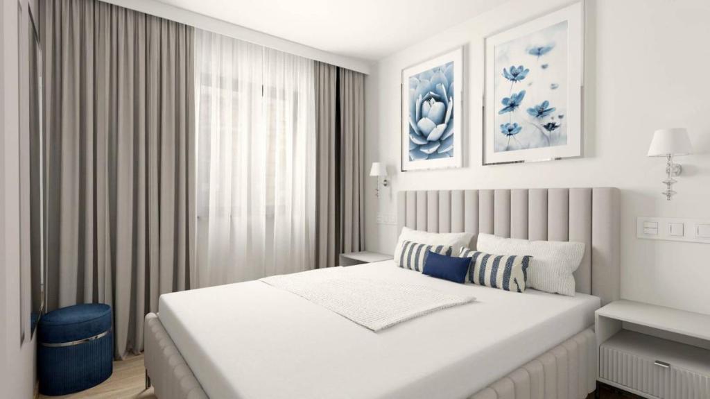 a white bedroom with a large bed and a window at A top-floor modern apartment Located 100 meters from the beach in Fuengirola