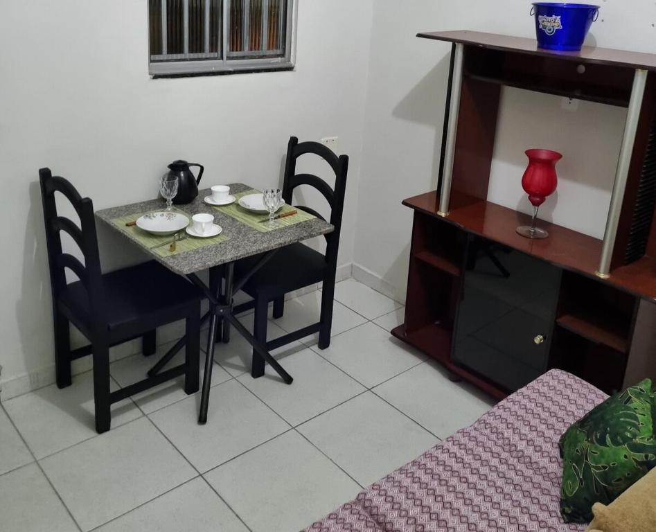a dining room table with two chairs and a table with plates on it at Lara 1 in Vitória da Conquista