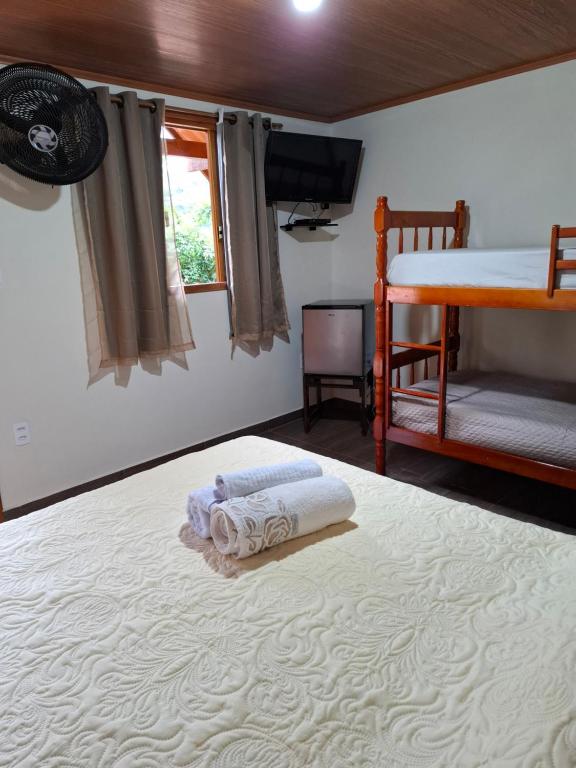 a bedroom with a bed with towels on it at Recanto Casa Amarela de São Romão in Nova Friburgo