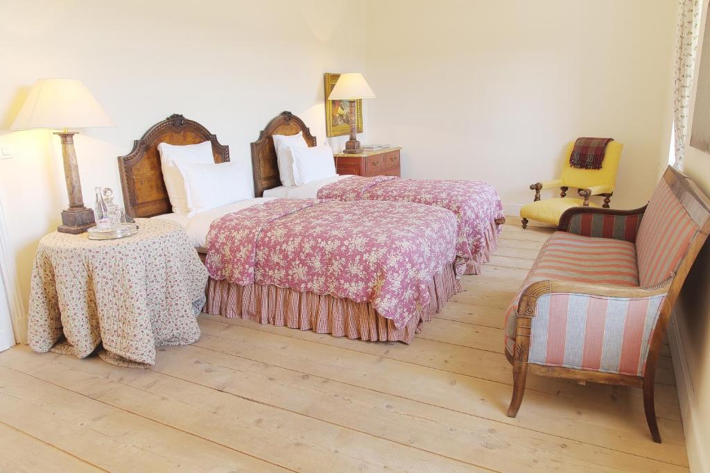 a bedroom with two beds and a chair and a couch at Château du Tertre in Arsac