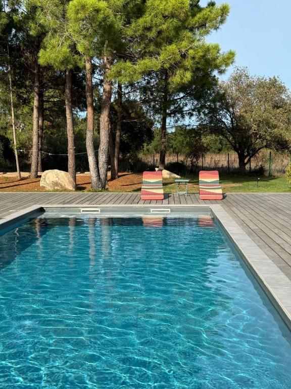 une piscine avec deux chaises longues et des arbres dans l'établissement Villa Casa di sognu, à Lecci