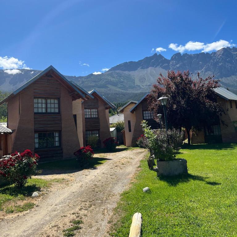 a house on a dirt road with mountains in the background at Aldea Bolsón in El Bolsón