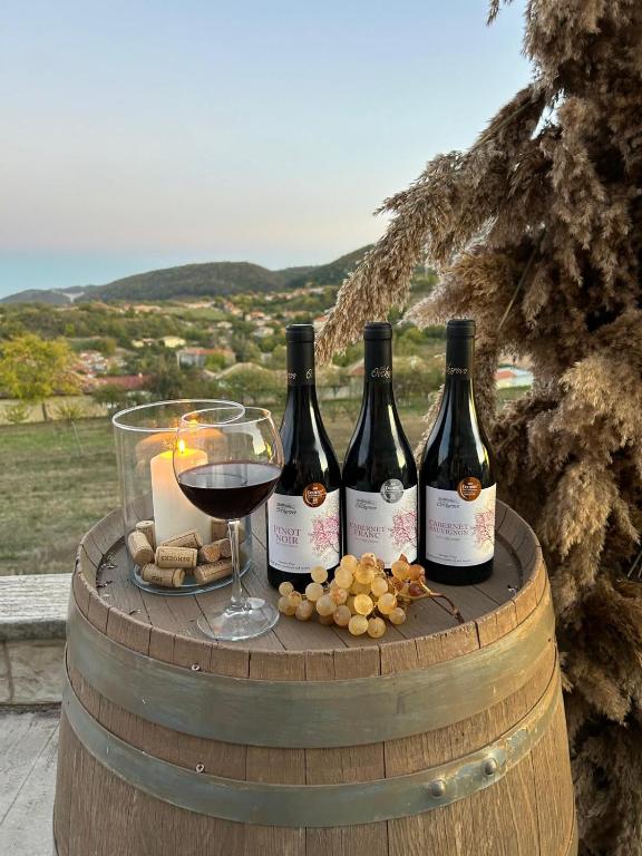 three bottles of wine and a glass on a barrel at Villa Ovcharovo in Targovishte
