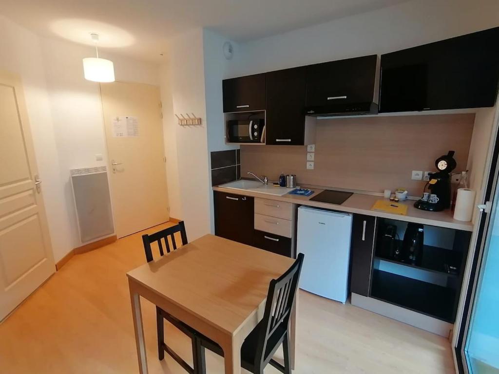 une cuisine avec une table en bois et une table et des chaises dans l'établissement Appartement avec balcon, Ax-Les-Thermes, à Ax-les-Thermes