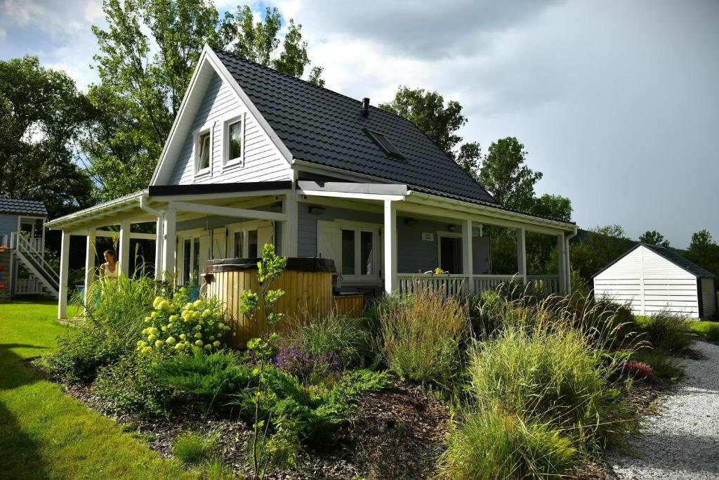 a white house with a porch and some plants at Domki z jacuzzi Dolny Śląsk noclegi premium Osada Aurora in Miszkowice
