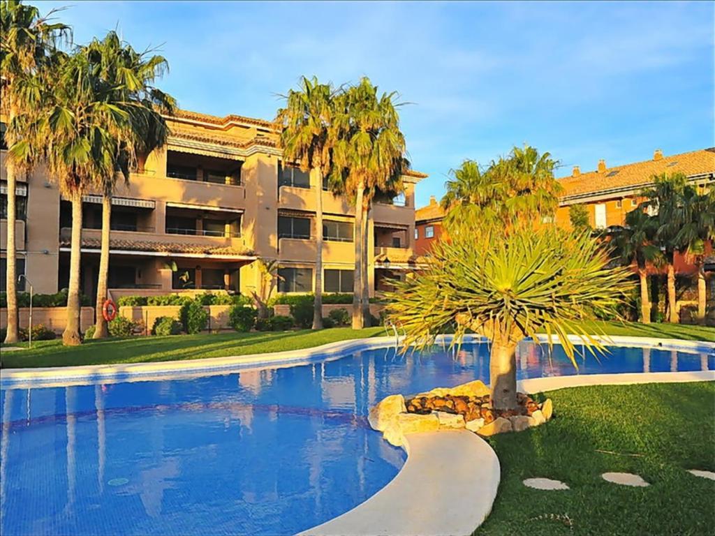 a swimming pool with a palm tree in front of a building at Apartment Perfect Holiday in Jávea