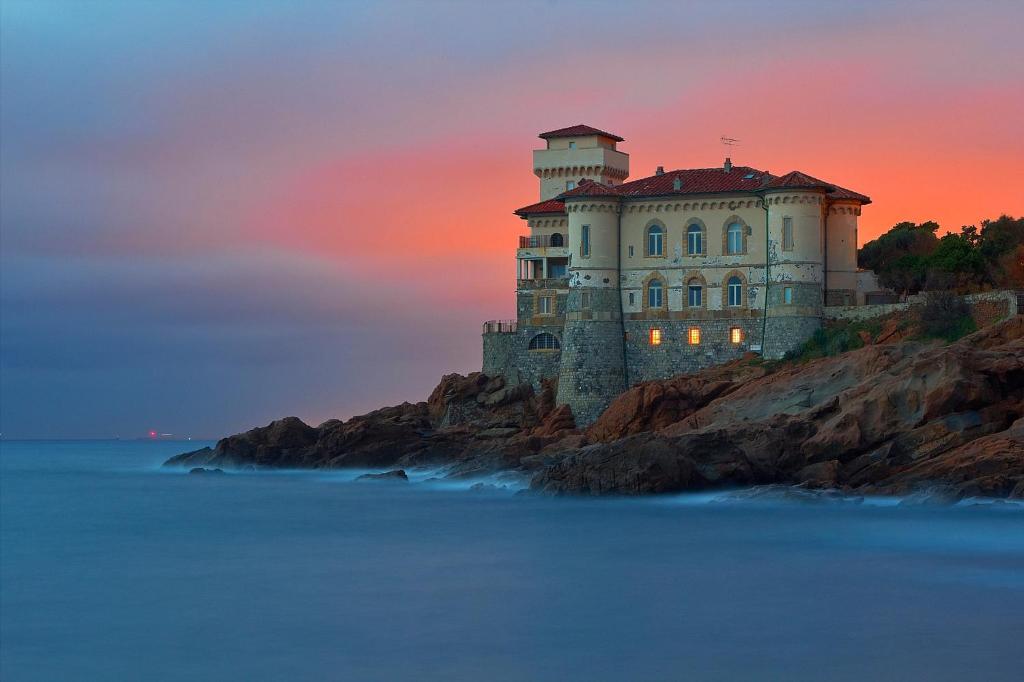 a castle on a cliff in the ocean at sunset at Cozy Stay in City Center in Livorno