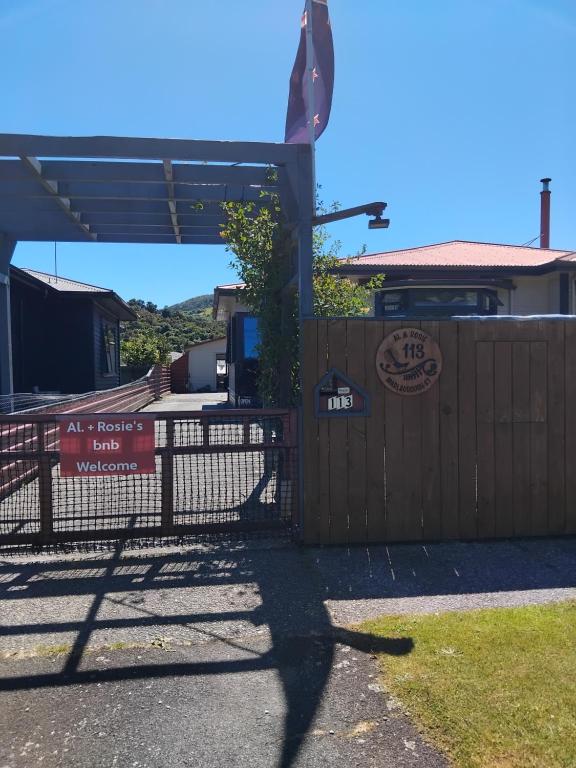 una valla delante de un edificio con un cartel en Al and Rosies B+B, en Greymouth