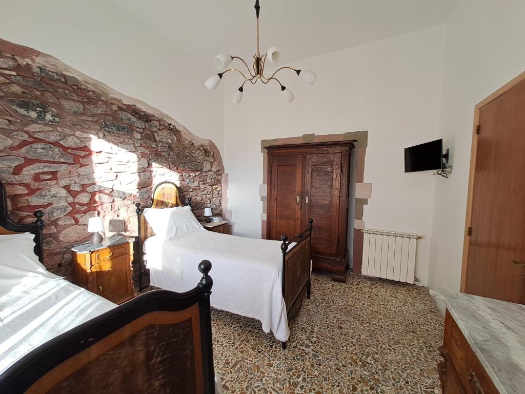 a bedroom with two beds and a stone wall at La Casa di Zietta in Santu Lussurgiu