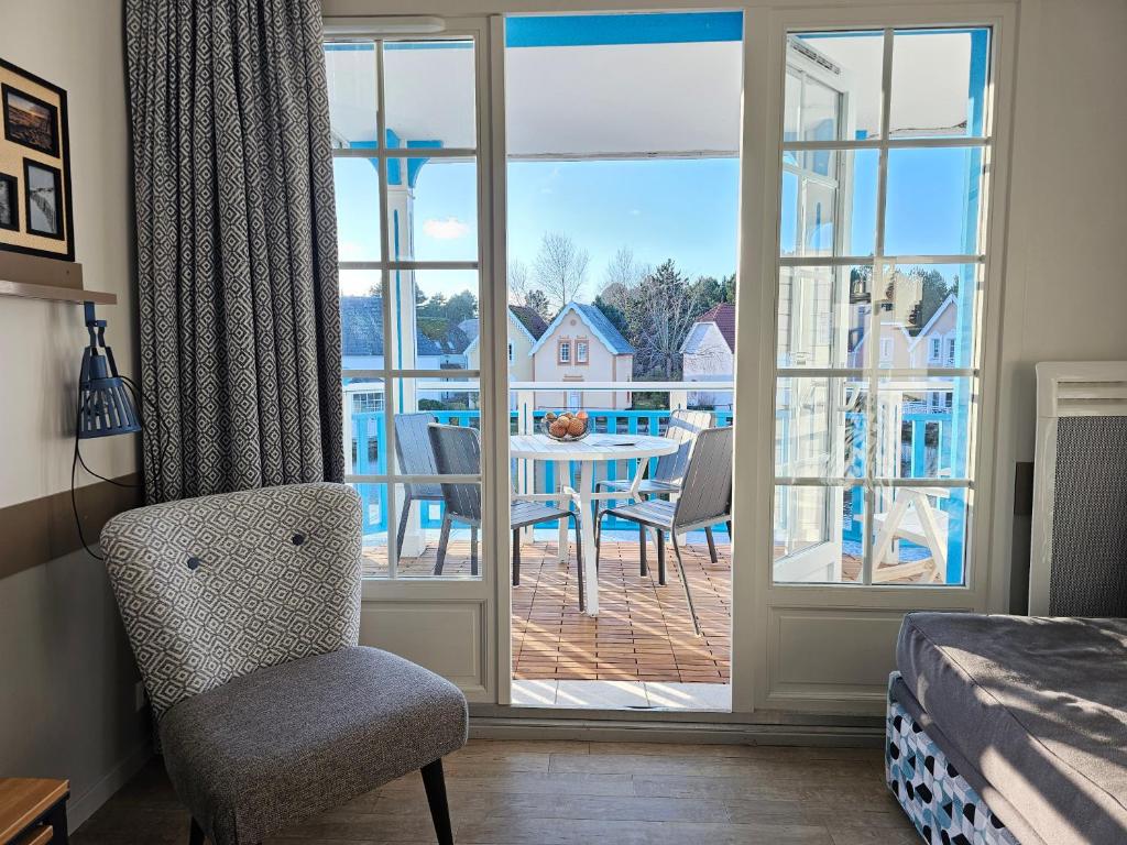 Un dormitorio con una puerta que da a un patio con mesa y sillas. en Charme Studio 103 Belle Dune, en Fort-Mahon-Plage