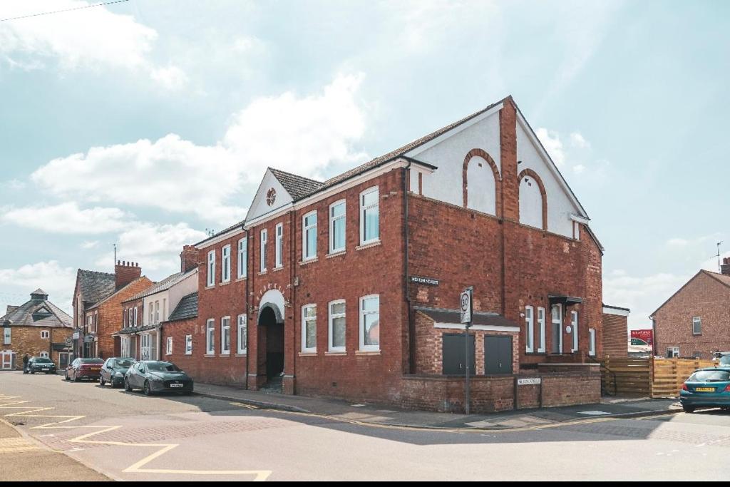 a large brick building with a cross on the side of it at The Old Band Accommodation 1 kingsize bed and 1 Sofa Bed available in Higham Ferrers
