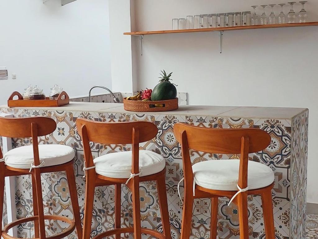 a kitchen with three wooden stools in front of a counter at Home Villa in Lovina