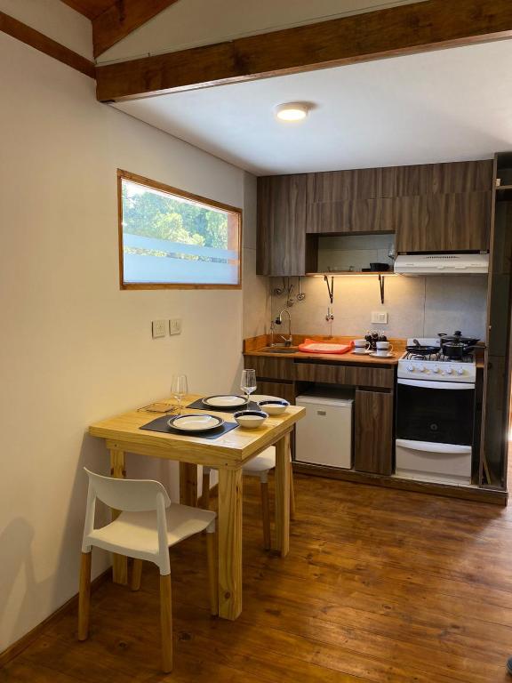 a kitchen with a wooden table and a table and chairs at Viví Bosque in San Carlos de Bariloche