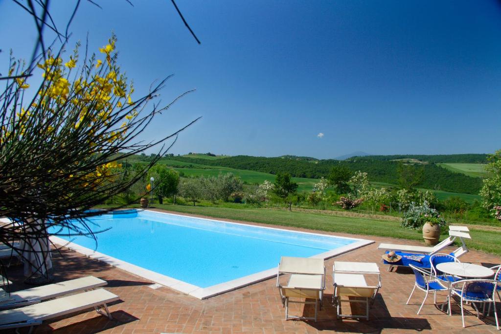 a swimming pool with chairs and a table and a tablektop at Agriturismo Il Casalone in Montepulciano