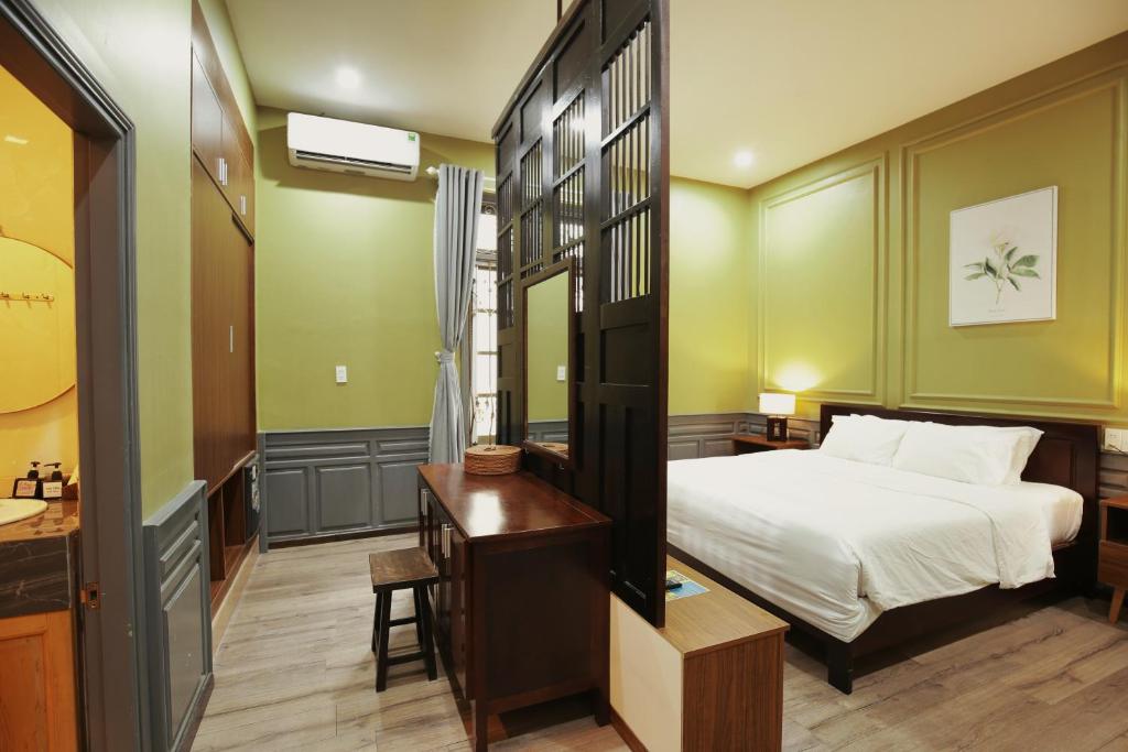 A bedroom view with a compact desk beside the bed and a visible bathroom entrance.