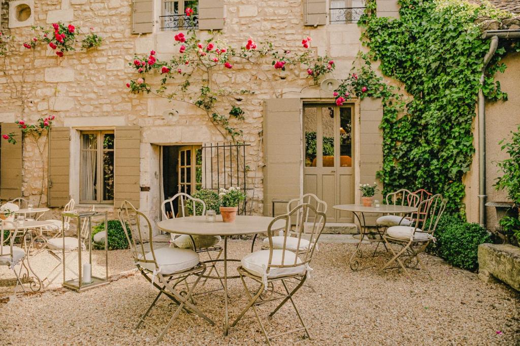 un patio avec des tables et des chaises en face d'un bâtiment dans l'établissement La Maison du Village, à Saint-Rémy-de-Provence