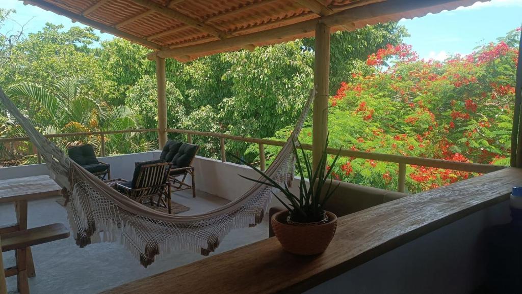 a porch with two chairs and a hammock on it at Hostel X DE CARAIVA in Caraíva