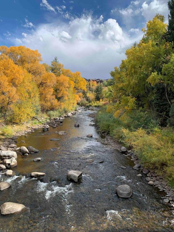 a river with rocks and trees in the background at Renovated condo steps from Beaver Creek shuttle in Avon
