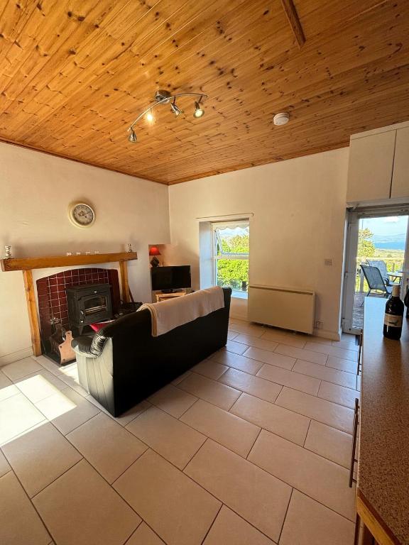a living room with a couch and a fireplace at Sunrise Mist Cottage in Garinish West