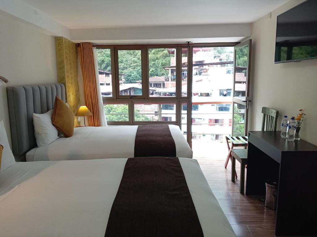 マチュピチュにあるHotel Pucara Machupicchuのベッド2台と机と窓があるホテルの部屋