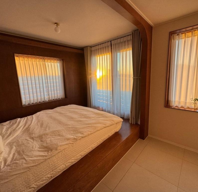 a bedroom with a large bed and two windows at 영도 여는 in Busan