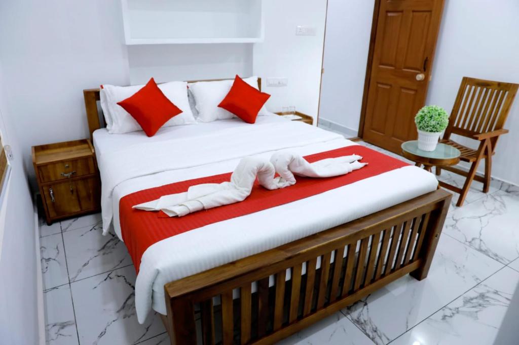 a bedroom with a large bed with red pillows at AMAN Residency in Kallar Vattiyar