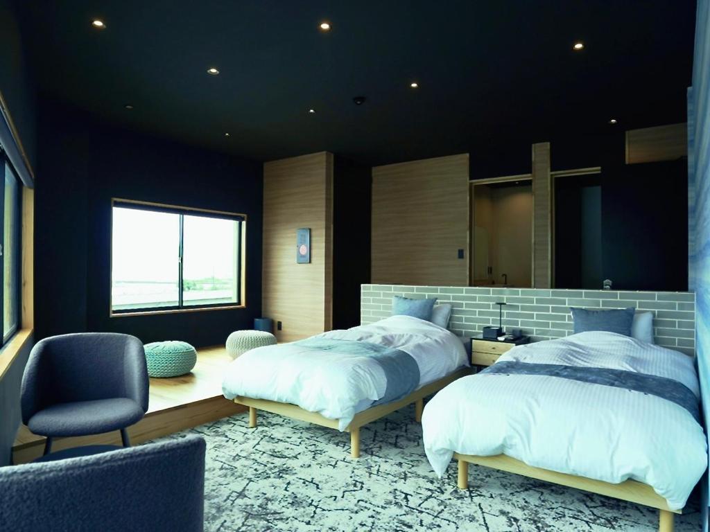 a bedroom with two beds and a chair at 1 and Only Hotel Io - イオ in Minamiise