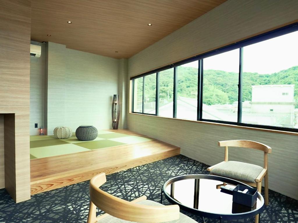 a room with a table and a chair and windows at 1 and Only Hotel Io - イオ in Minamiise