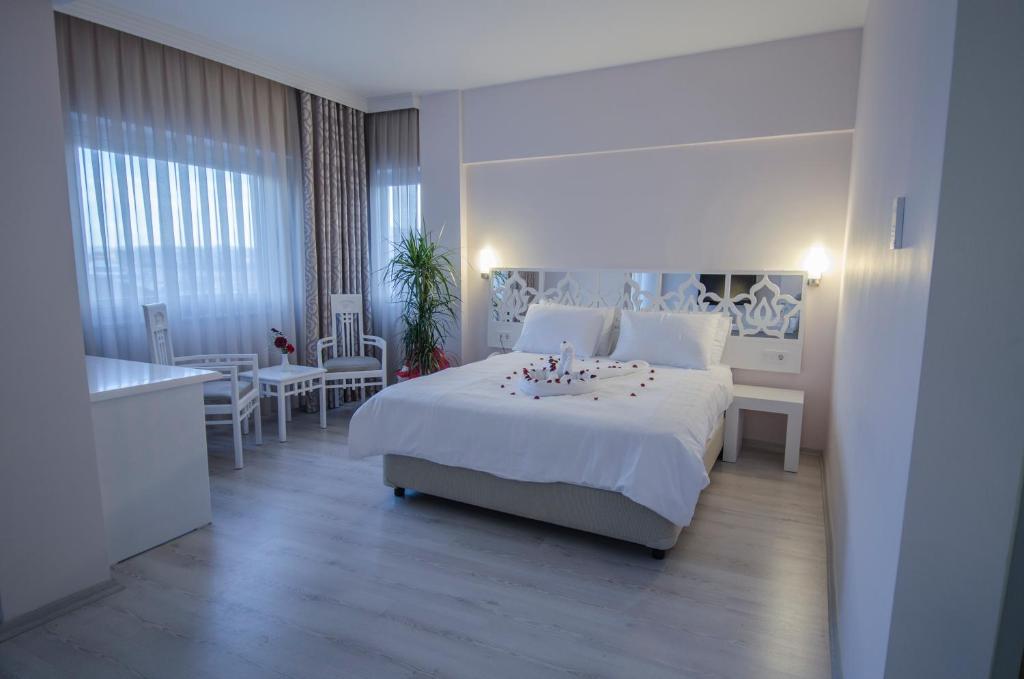 Cimenoglu Hotel في دنيزلي: غرفة نوم بسرير ابيض وطاولة وكراسي