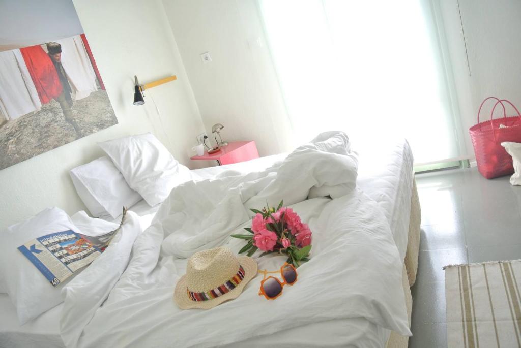 uma cama branca com um chapéu e flores em Yucca Alaçatı em Alacati