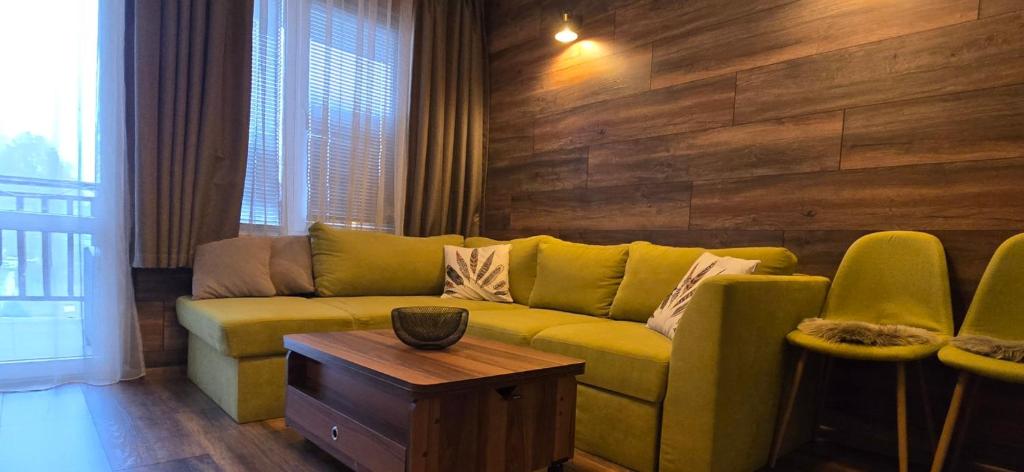 a living room with a yellow couch and a table at Апартамент Edelweiss in Beli Iskar