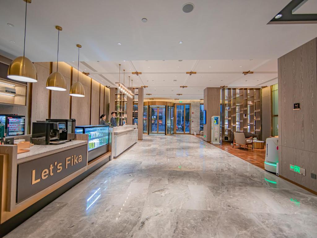 襄陽市にあるXiangyang Station Minfa World City Yishang Plus Hotelの廊下の長い店舗のロビー