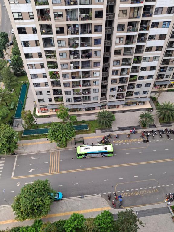 un autobus che passa per una strada di fronte a un grande edificio di Khu đô thị Vinhomes Grand Park Tp Thủ đức Tp HCM a Long Bình