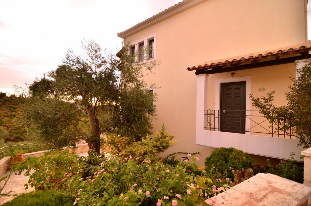 a house with a balcony and a tree at Niriides Luxury Apartments in Syvota