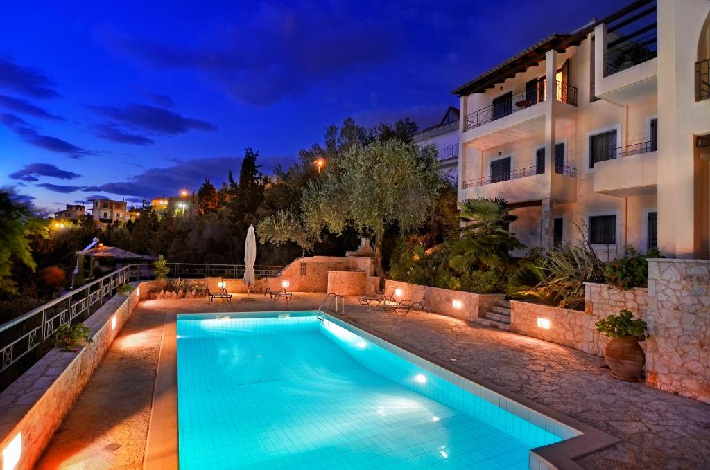 a swimming pool in front of a building at night at Niriides Luxury Apartments in Syvota