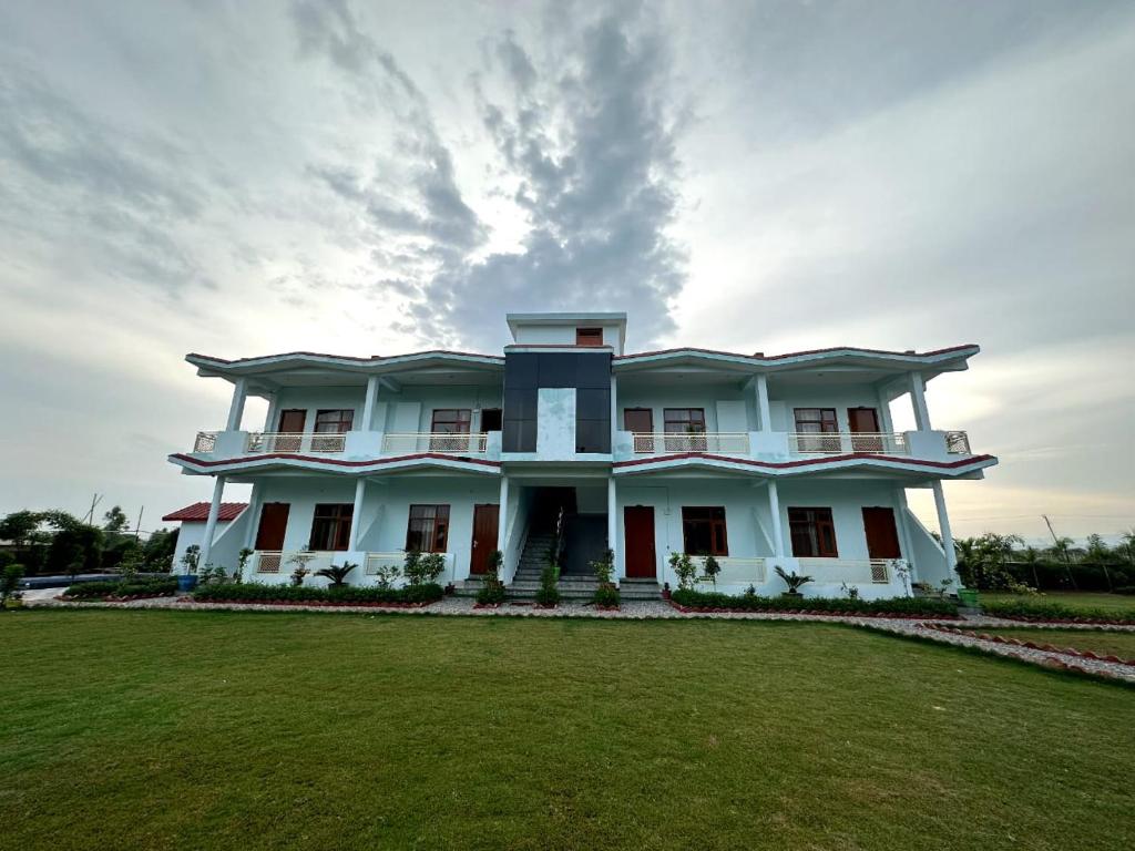 una grande casa bianca con un ampio cortile di Kuyal Corbett Resort a Ramnagar